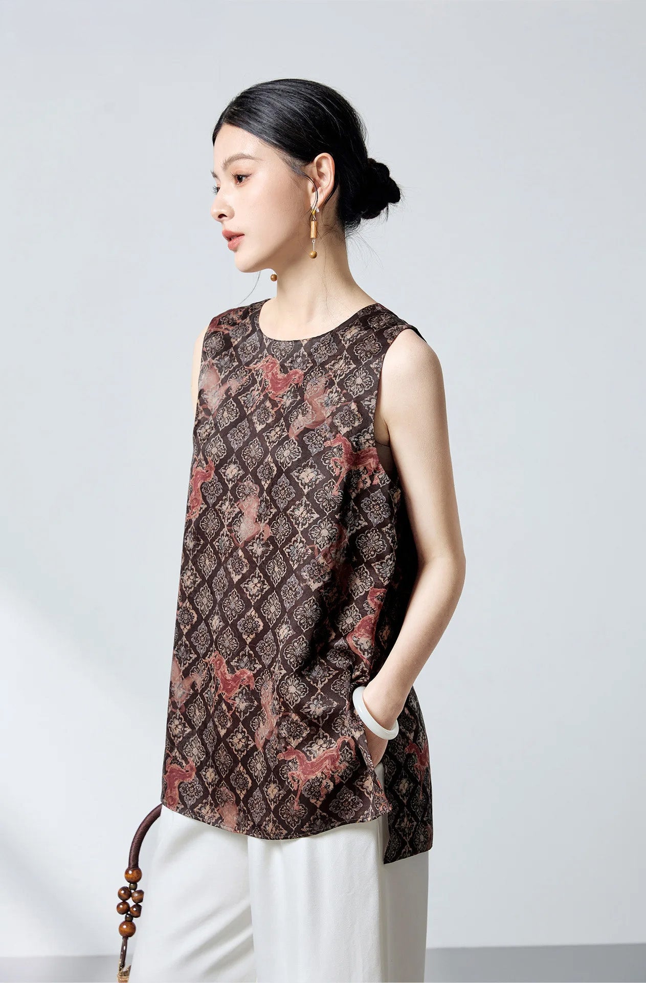 Model turned slightly to the side wearing the Fire Steeds Xiangyunsha silk jacquard top in espresso and terracotta — From Borcelleclothes.