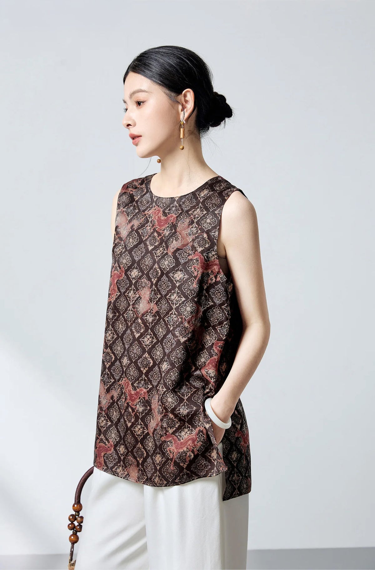 Model turned slightly to the side wearing the Fire Steeds Xiangyunsha silk jacquard top in espresso and terracotta — From Borcelleclothes.