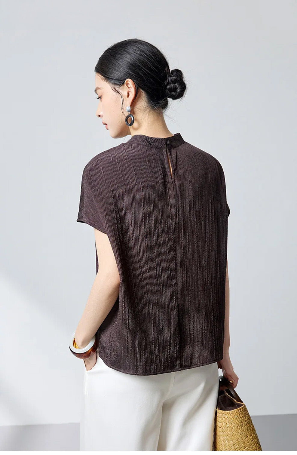 Back view of model wearing dark brown fluted jacquard silk blouse by Borcelleclothes.