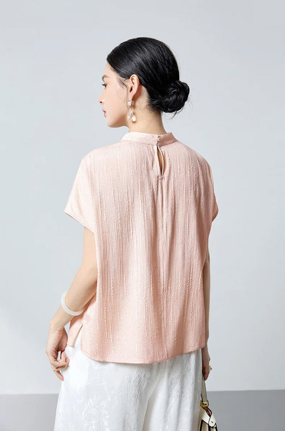 Rear view of model wearing falling memories fluted jacquard silk blouse by Borcelleclothes.