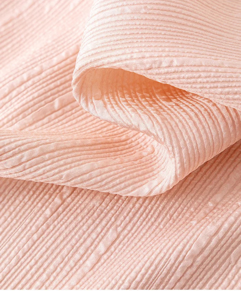 Close-up of wave-folded texture on 100% pink fluted jacquard silk fabric by Borcelleclothes.