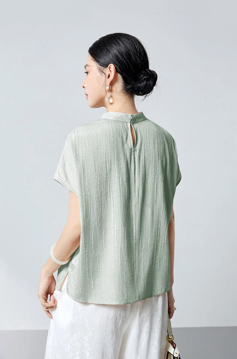 Back view of model wearing mint green fluted silk blouse by Borcelleclothes.