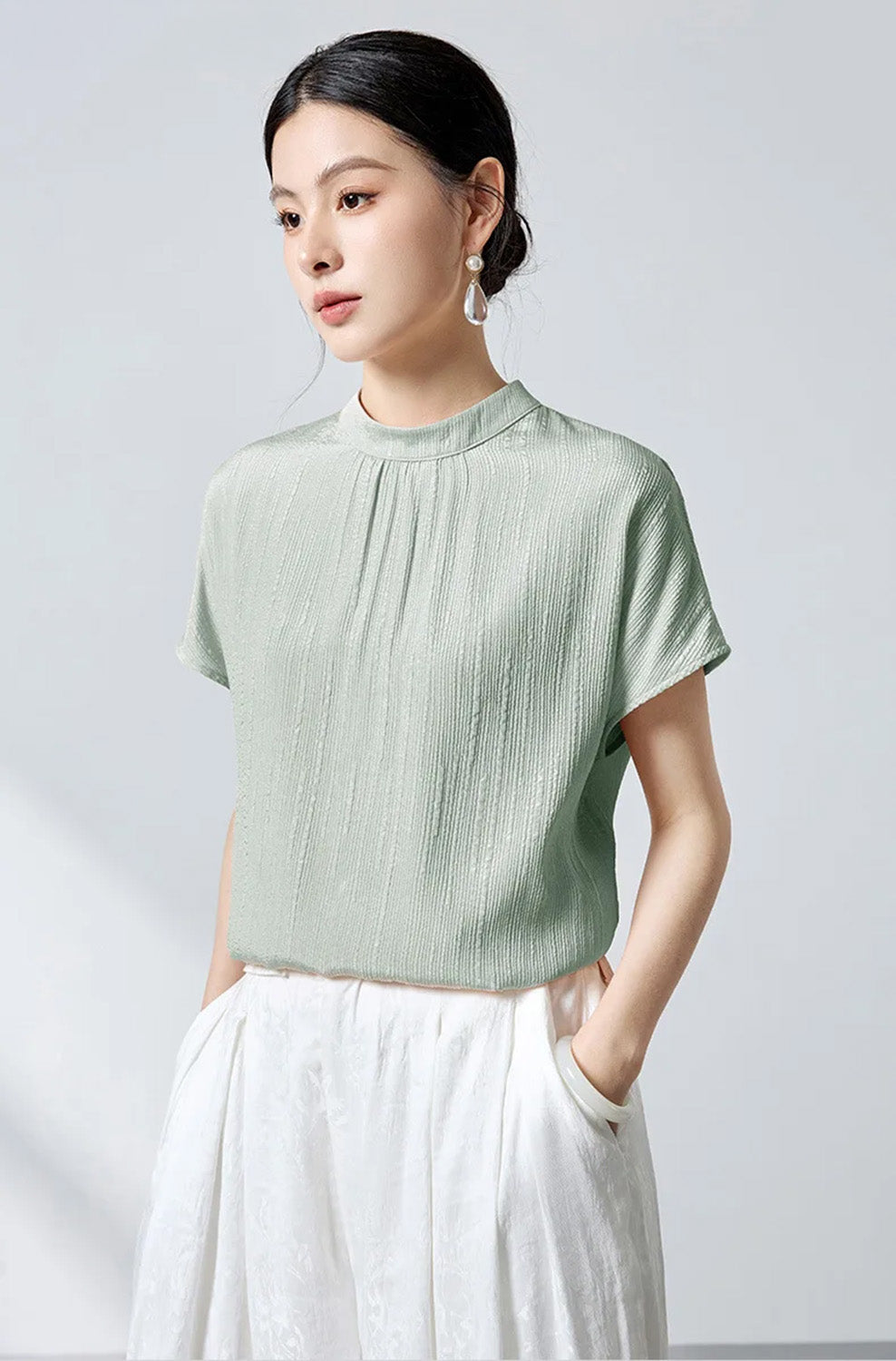 Model with hands in pants pockets wearing mint green jacquard silk blouse by Borcelleclothes.