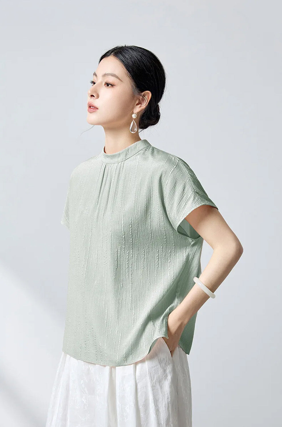 Side profile of model dressed in mint fluted jacquard silk blouse by Borcelleclothes.