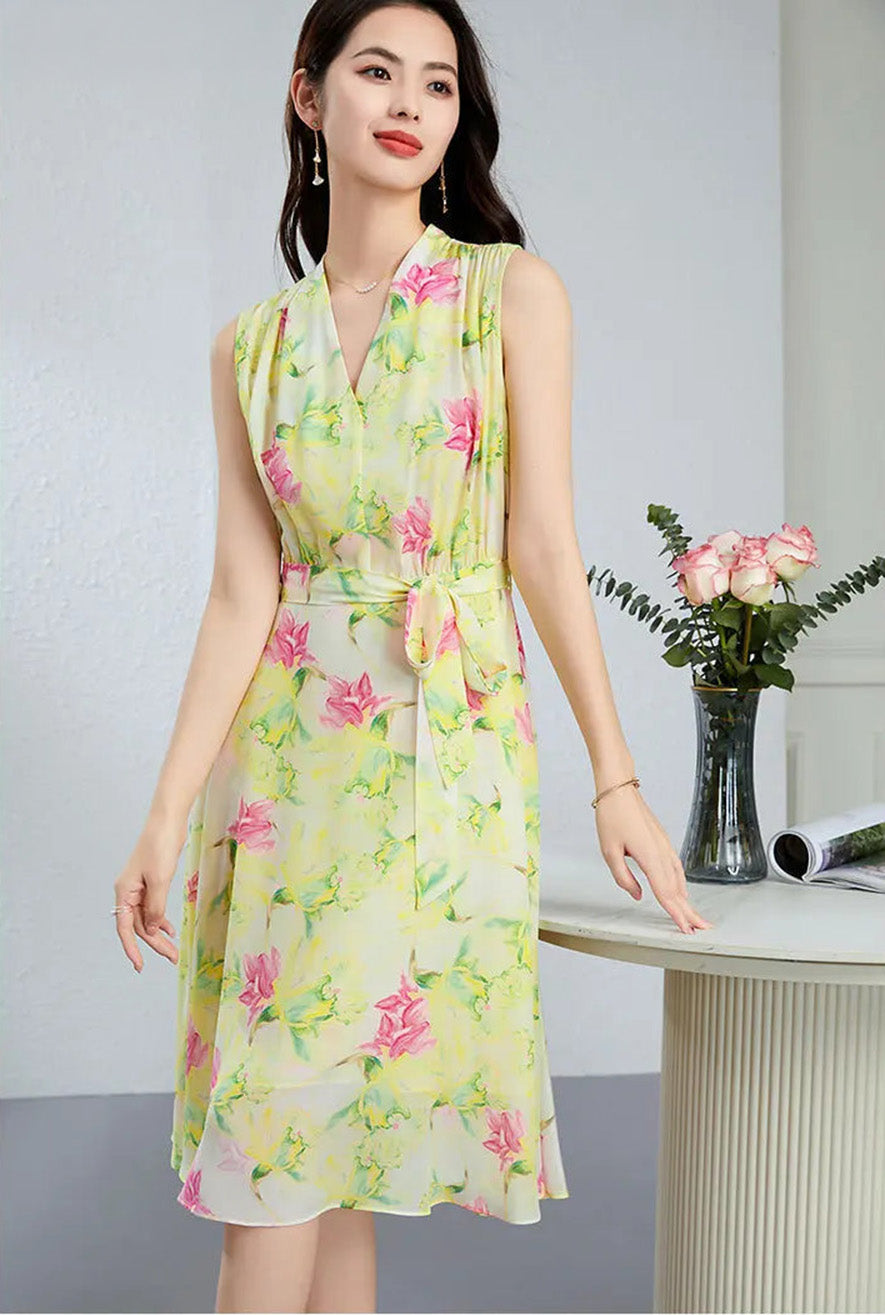 A woman in the Magnolia in May silk midi dress, resting her fingertips on a table to showcase the elegant drape and continuous-cut collar — From Borcelleclothes.