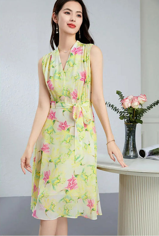 A woman in the Magnolia in May silk midi dress, resting her fingertips on a table to showcase the elegant drape and continuous-cut collar — From Borcelleclothes.