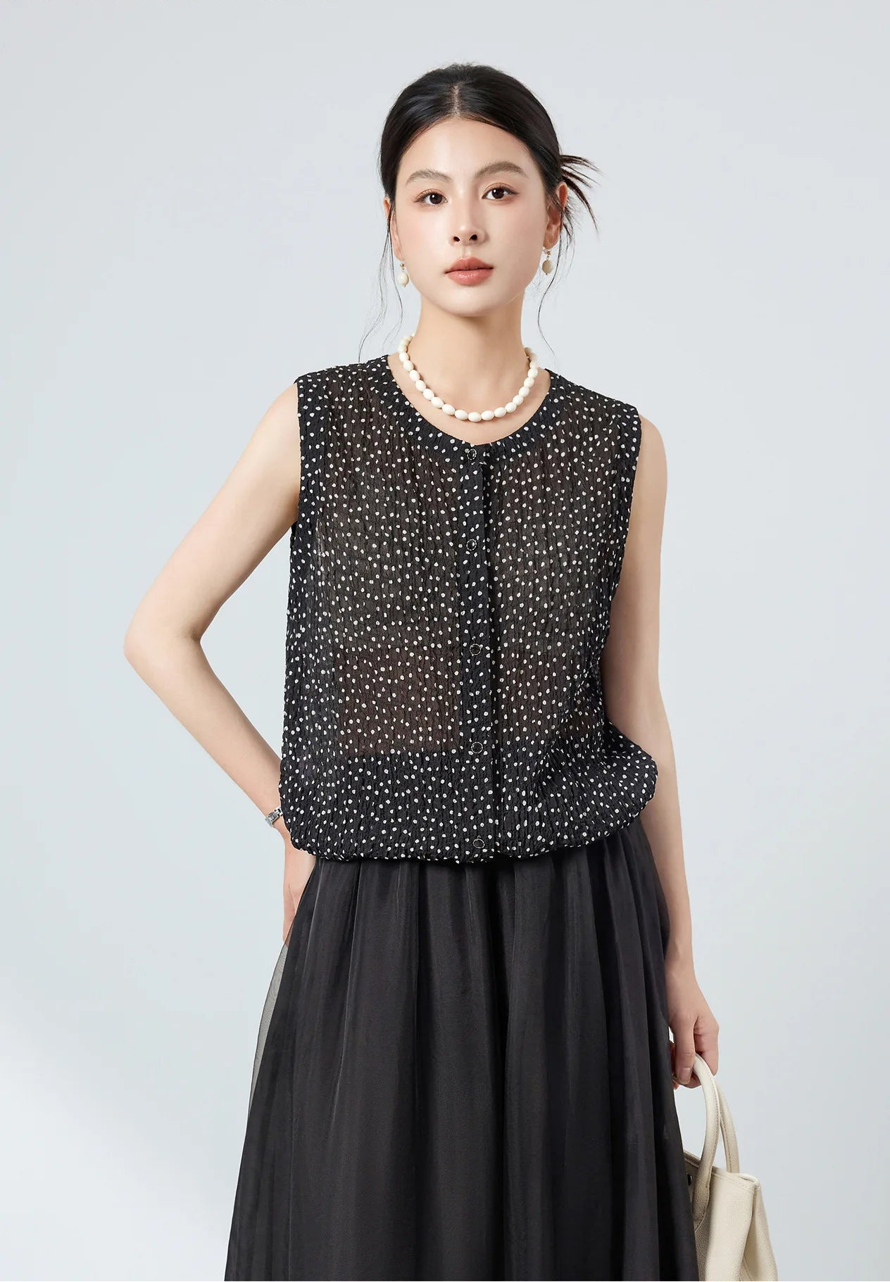 Front view of sleeveless polka dot 3D puckered silk blouse worn with buttons forward — From Borcelleclothes.