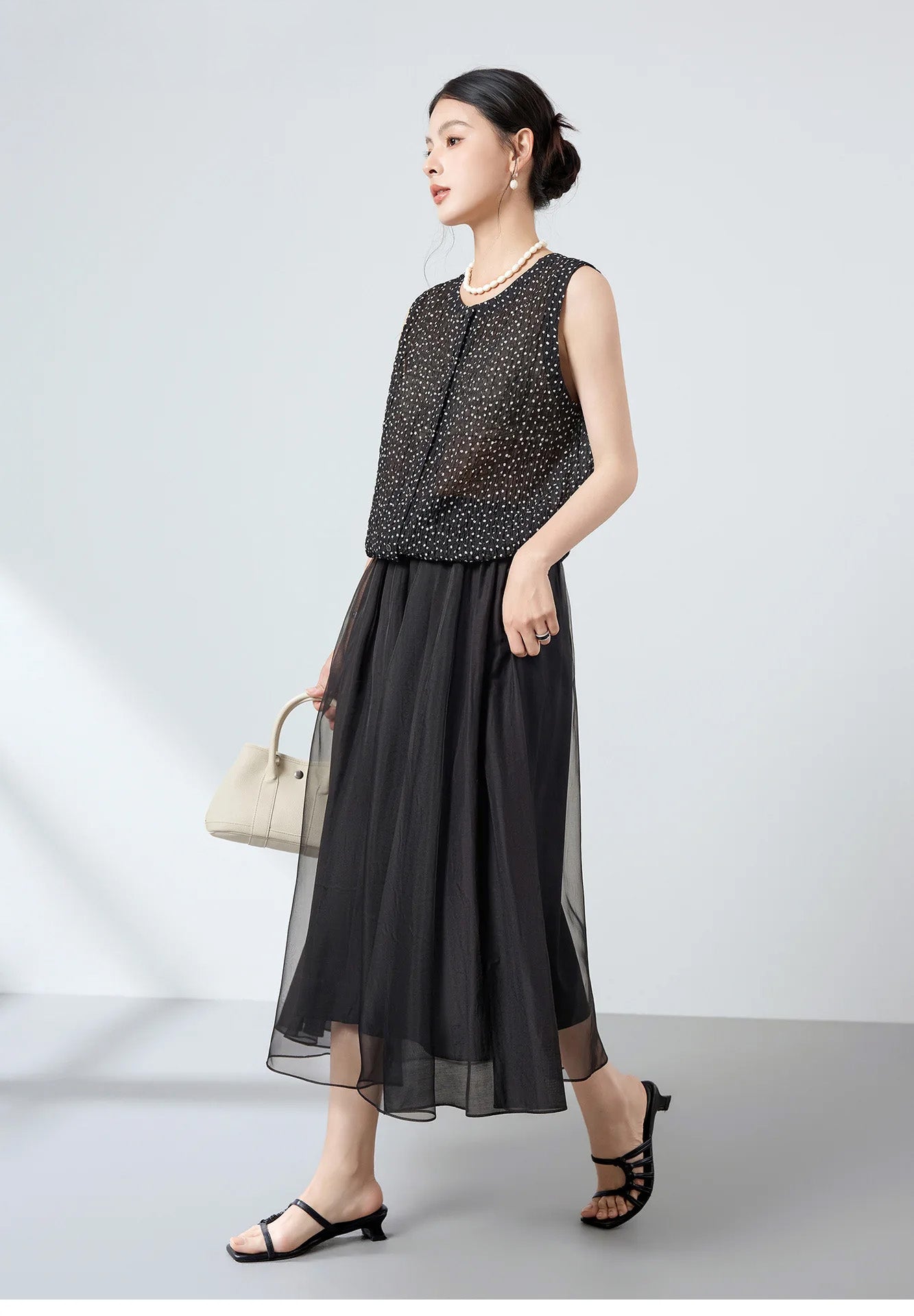 Side profile of model walking in sleeveless 3D puckered jacquard silk blouse in Dans Tes Bras — From Borcelleclothes.