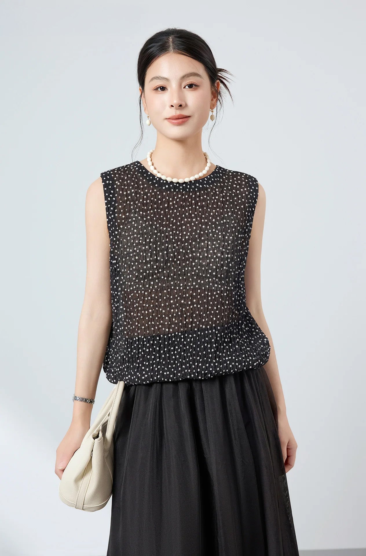 Studio portrait of model wearing black polka dot silk blouse styled with buttons at the back — From Borcelleclothes.