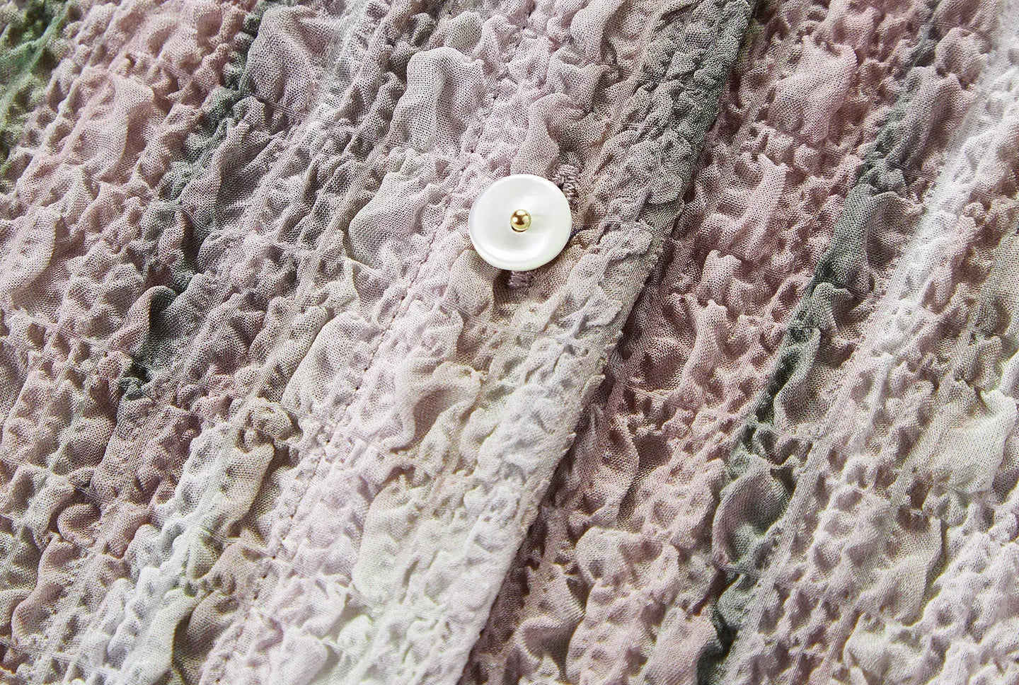 Close-up of natural satin-finish mother-of-pearl button on 3D puckered silk jacquard — From Borcelleclothes.