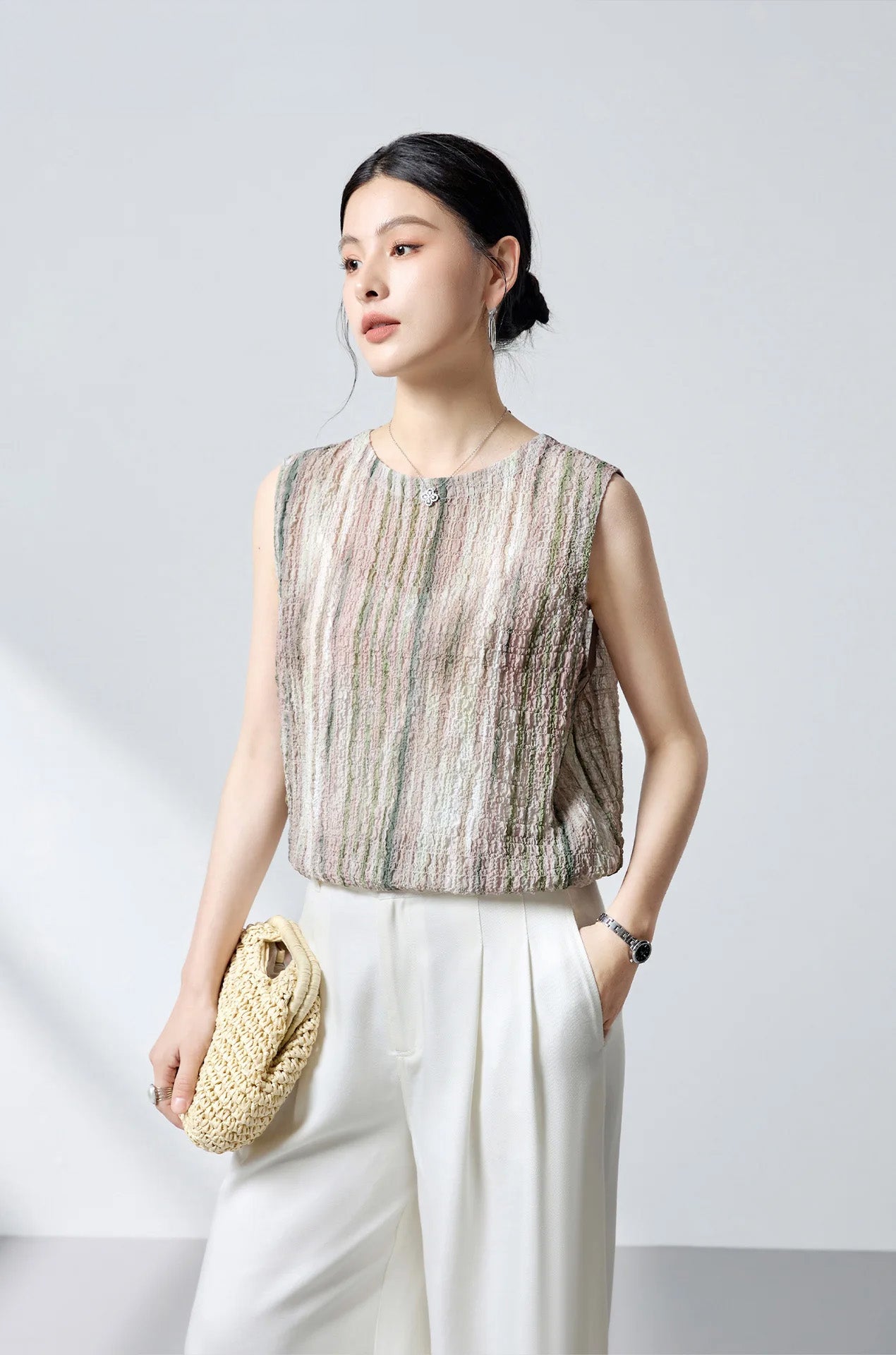 Model holding a woven bag wearing the front-to-back silk blouse with buttons at the back — From Borcelleclothes.