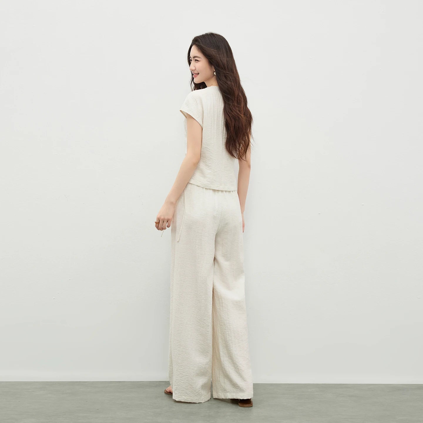 The back silhouette of a woman in the Ether de Marbre set, showing the clean lines and the fluid drape of the wide-leg trousers. — From Borcelleclothes.