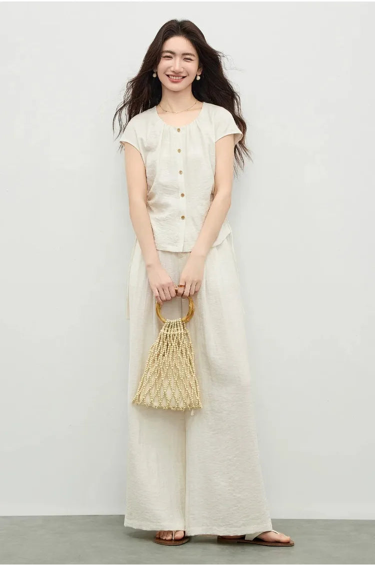 A woman accessorizing the Ether de Marbre set with a woven bag, embodying a natural, summer-ready aesthetic. — From Borcelleclothes.
