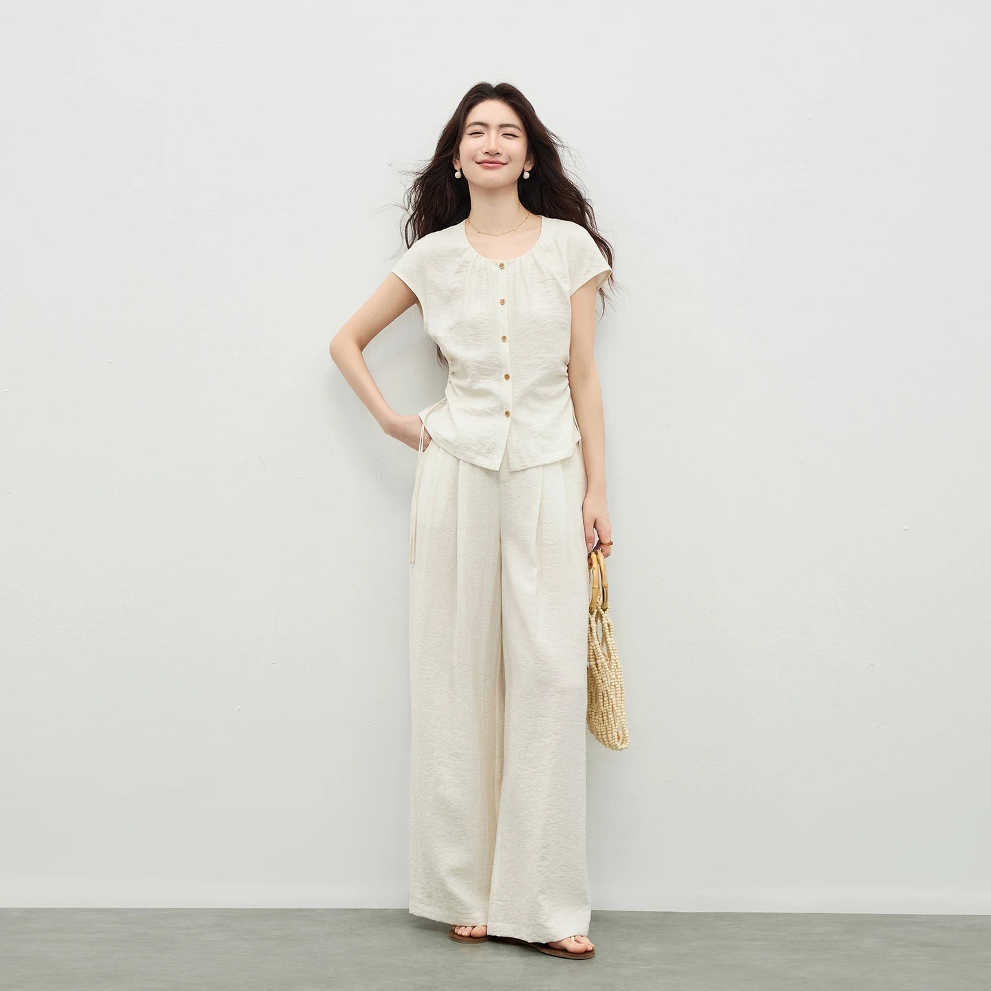 Women's ivory set in crinkled fabric, showing a sleeveless top with a gathered neck and drawstring waist, and matching wide-leg pants. — From Borcelleclothes.