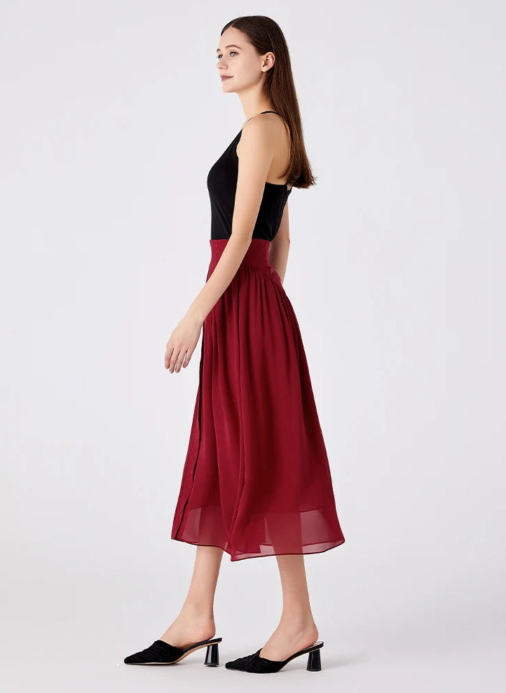 Side view of a model walking in a midi-length silk skirt with gathered georgette panels — From Borcelleclothes.