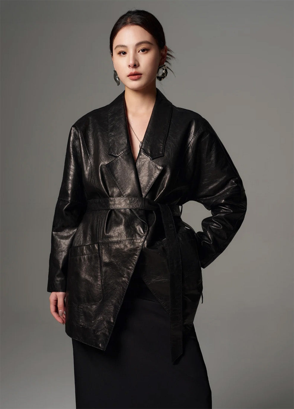 Model standing with hand behind back wearing the belted glazed goatskin wrap jacket in Vola Con Me — From Borcelleclothes.