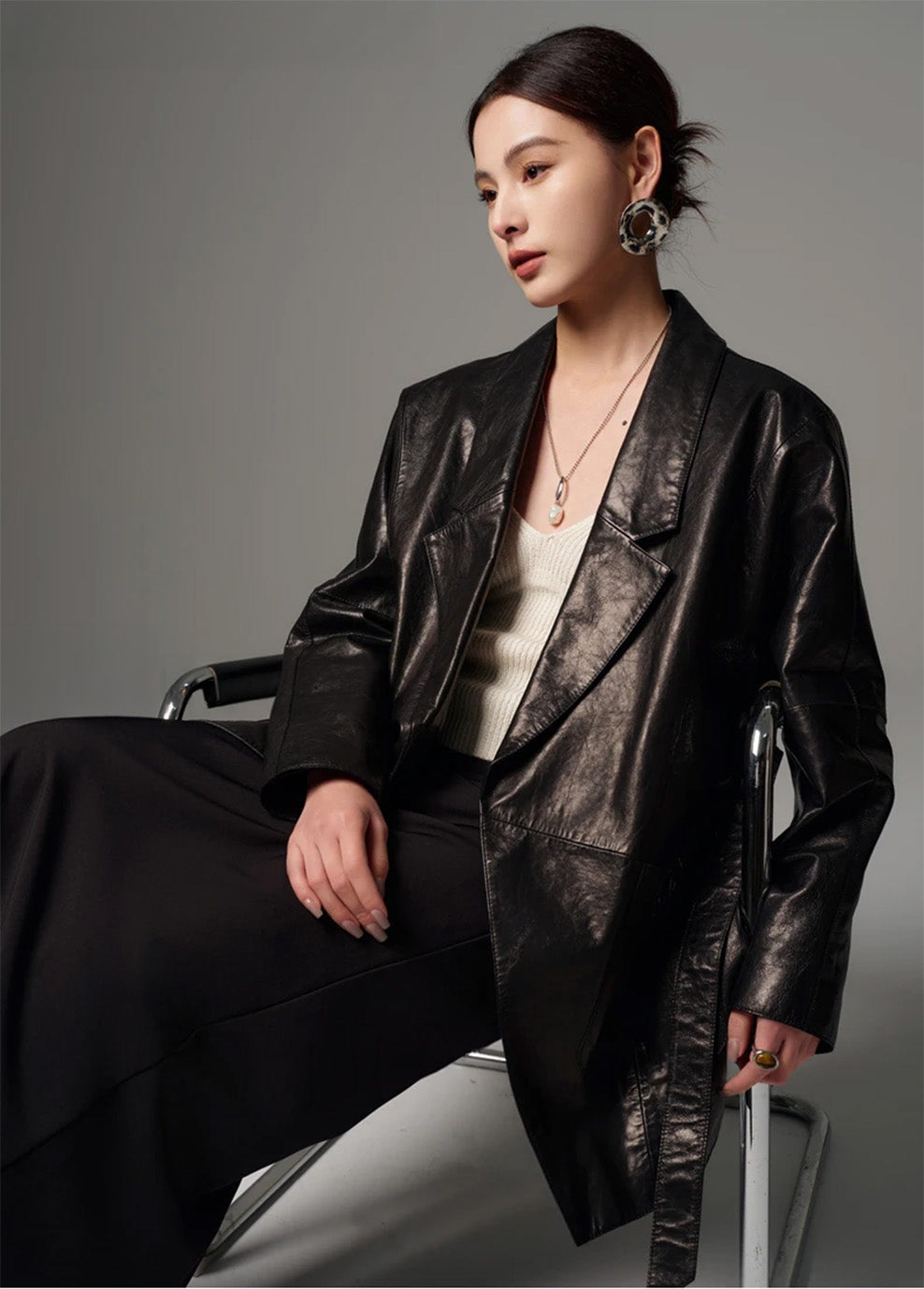Model sitting in a chair wearing the dark mercury glazed goatskin wrap jacket with stacked sleeve folds — From Borcelleclothes.
