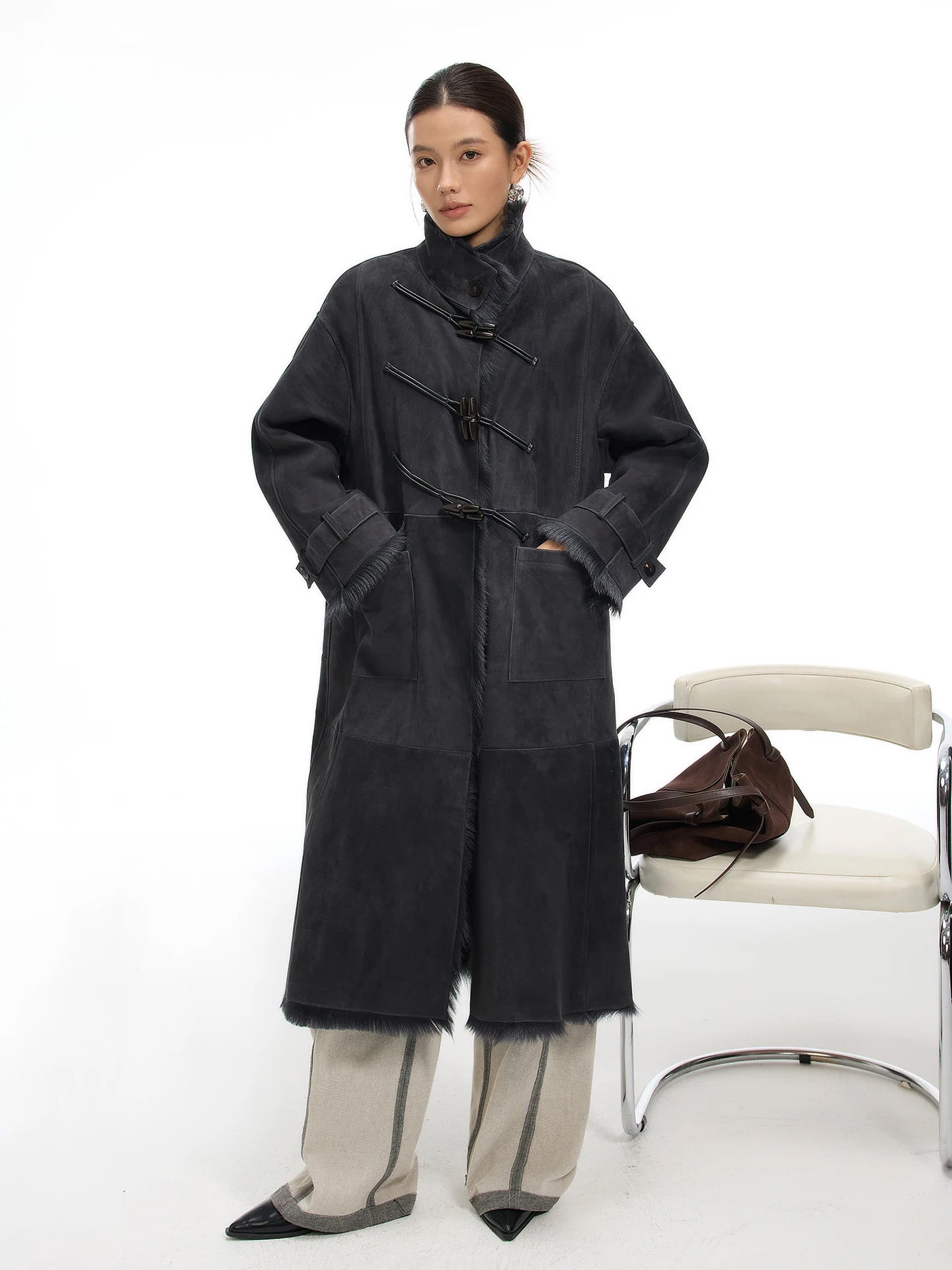 Model in goatskin coat, Inner Depth, standing with hands in side patch pockets; diagonal leather air loops and toggle closure accent front — From Borcelleclothes.