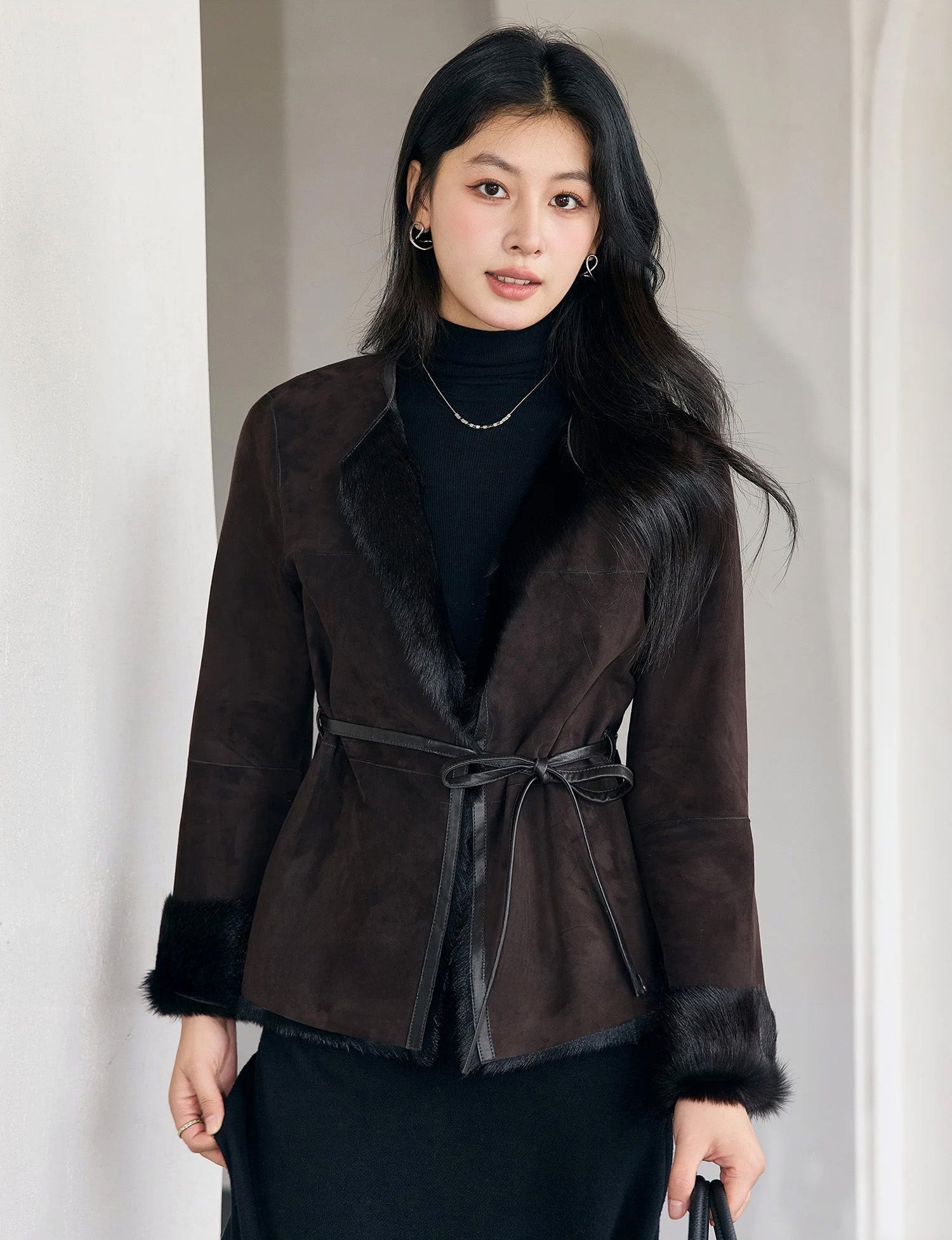 Model touching a black skirt while wearing the Tamarind goatskin jacket, highlighting texture contrast and hip length — From Borcelleclothes.