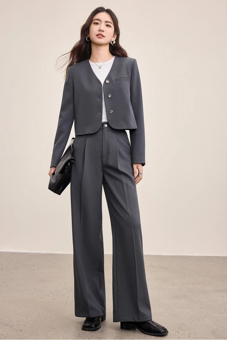 A woman carrying an oversized black bag, perfectly complementing the sharp lines of her Gris Phénix suit — From Borcelleclothes.