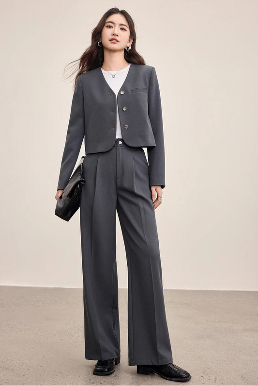 A woman carrying an oversized black bag, perfectly complementing the sharp lines of her Gris Phénix suit — From Borcelleclothes.
