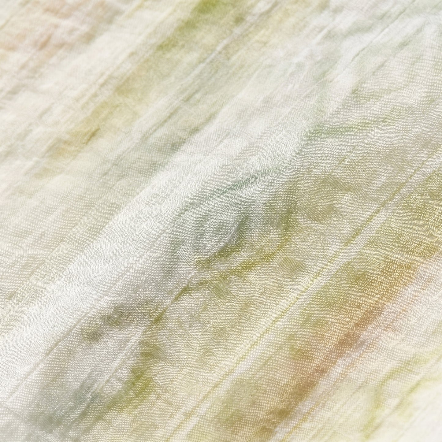 Macro view of the crinkled lyocell fabric featuring blurred geometric Ikat-inspired patterns in olive shades — From Borcelleclothes.