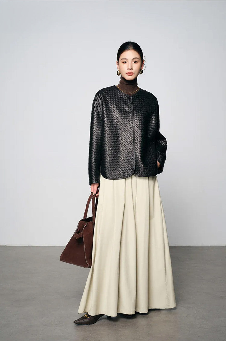 Model wearing black woven nappa jacket with hand resting in skirt pocket — From Borcelleclothes.