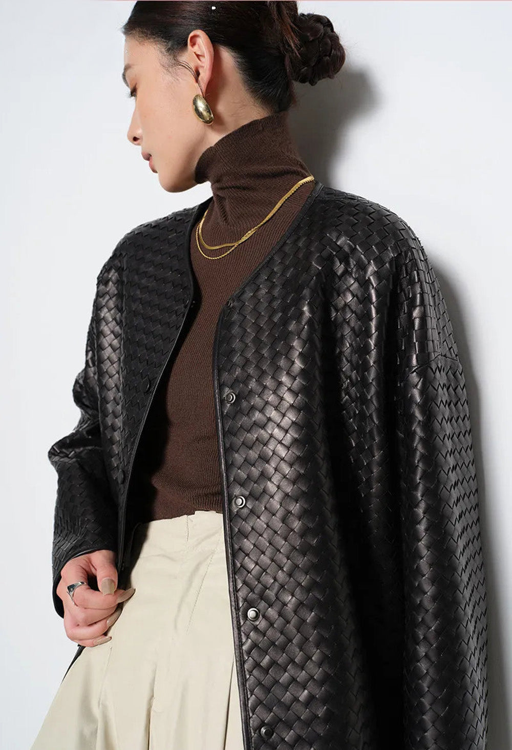 Side angle of model wearing black hand-woven sheepskin jacket looking away from camera — From Borcelleclothes.