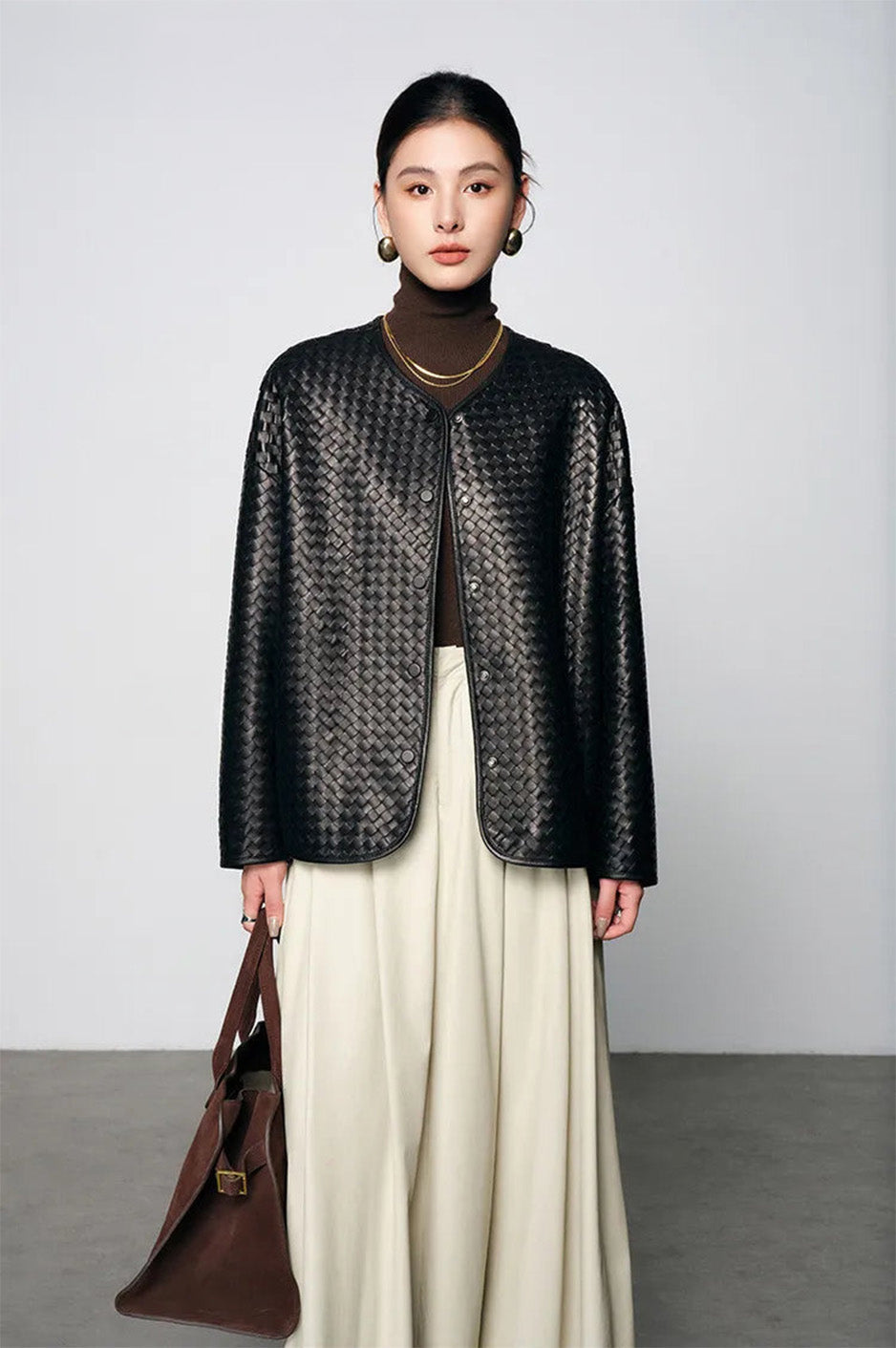 Unfastened hand-woven sheepskin jacket worn open on model holding handbag — From Borcelleclothes.