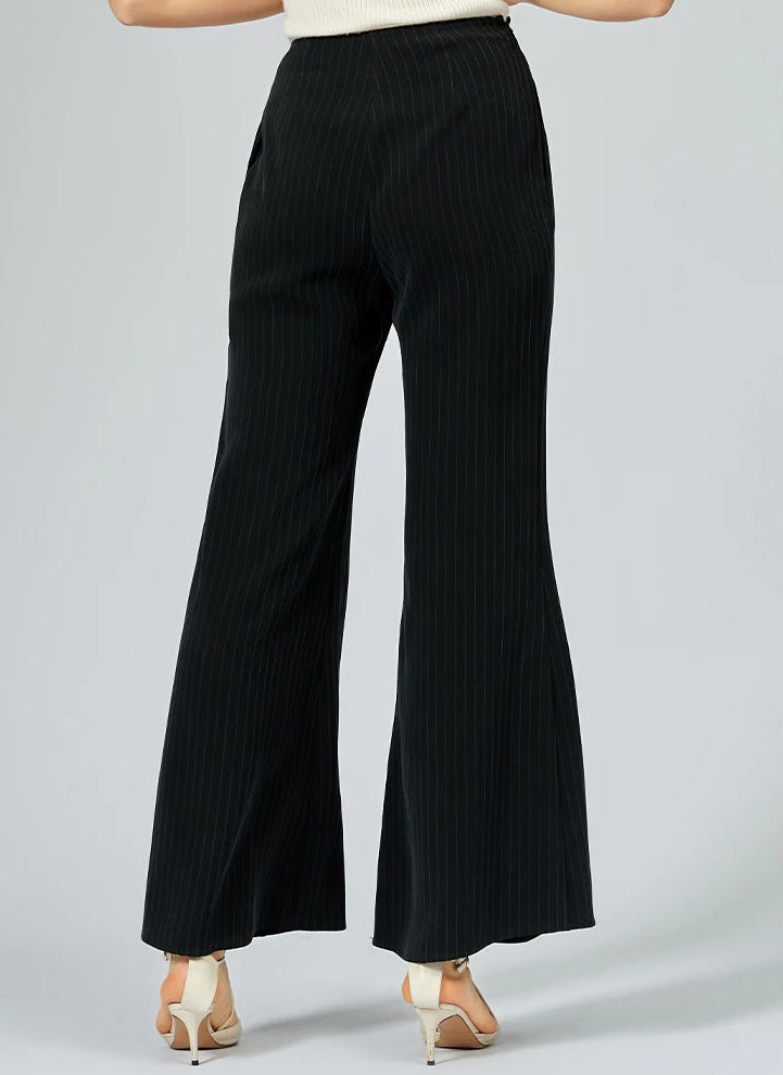 Back view of a woman wearing flared wide-leg pinstripe silk trousers — From Borcelleclothes.