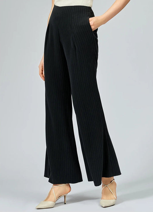 Woman posing in heavyweight pinstripe silk trousers with a hand in her pocket — From Borcelleclothes.