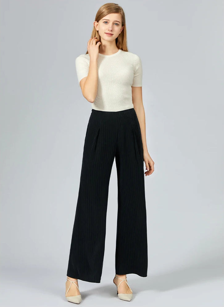 Woman in wide-leg pinstripe silk trousers touching her hair in an effortless pose — From Borcelleclothes.
