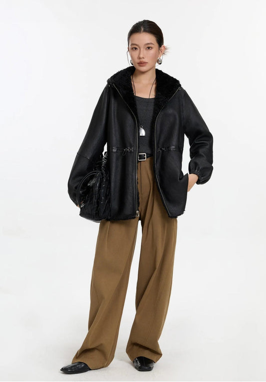 Model holding a bag, wearing the Night Swirling shearling coat with leather side out — From Borcelleclothes. 