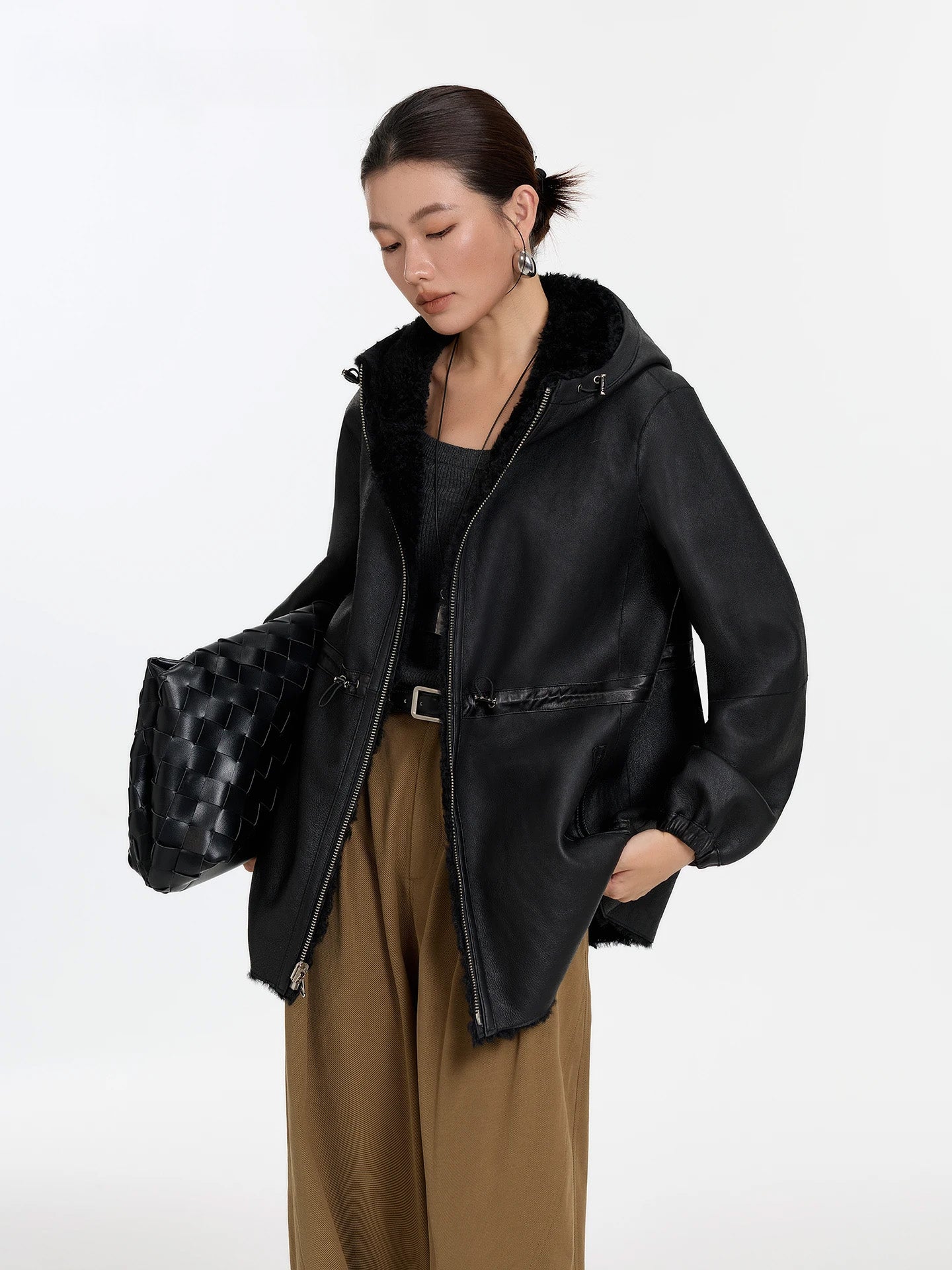 Model holding a bag and lifting the hem, Night Swirling coat, leather side — From Borcelleclothes.