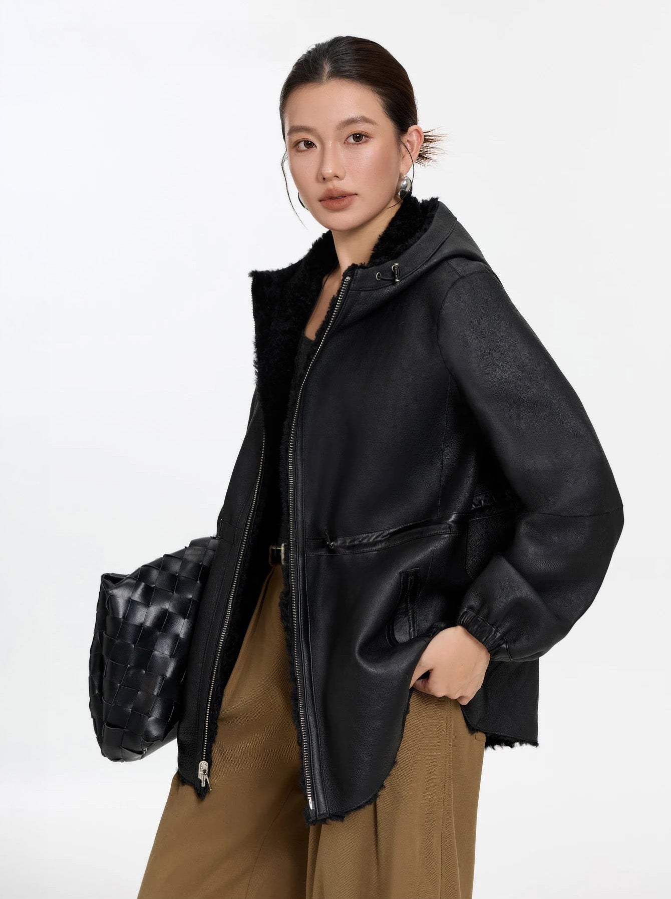 Model holding a bag and looking to the side, Night Swirling coat, leather side — From Borcelleclothes.