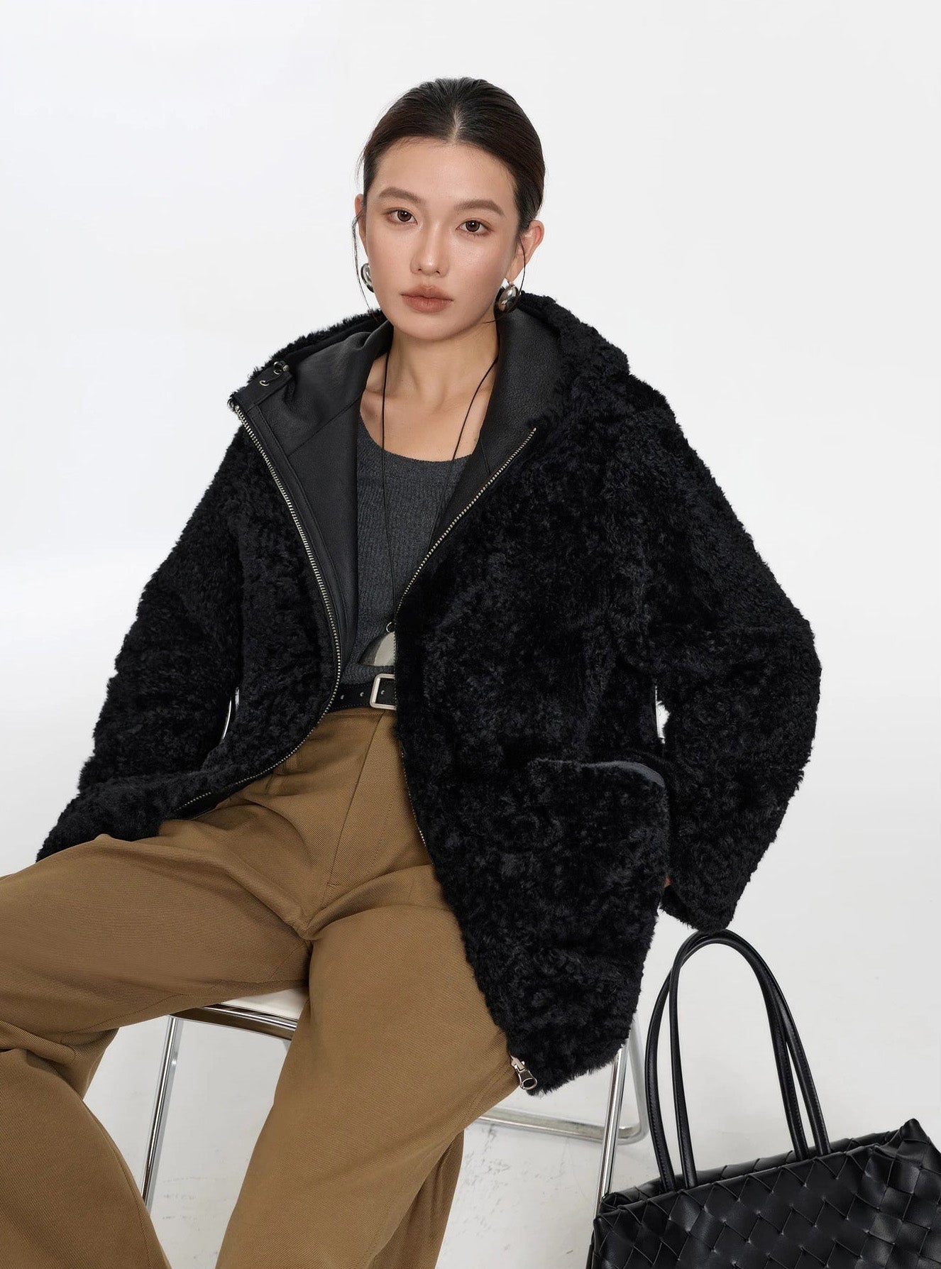 Model sitting on a chair, Night Swirling coat reversed to fur side — From Borcelleclothes.