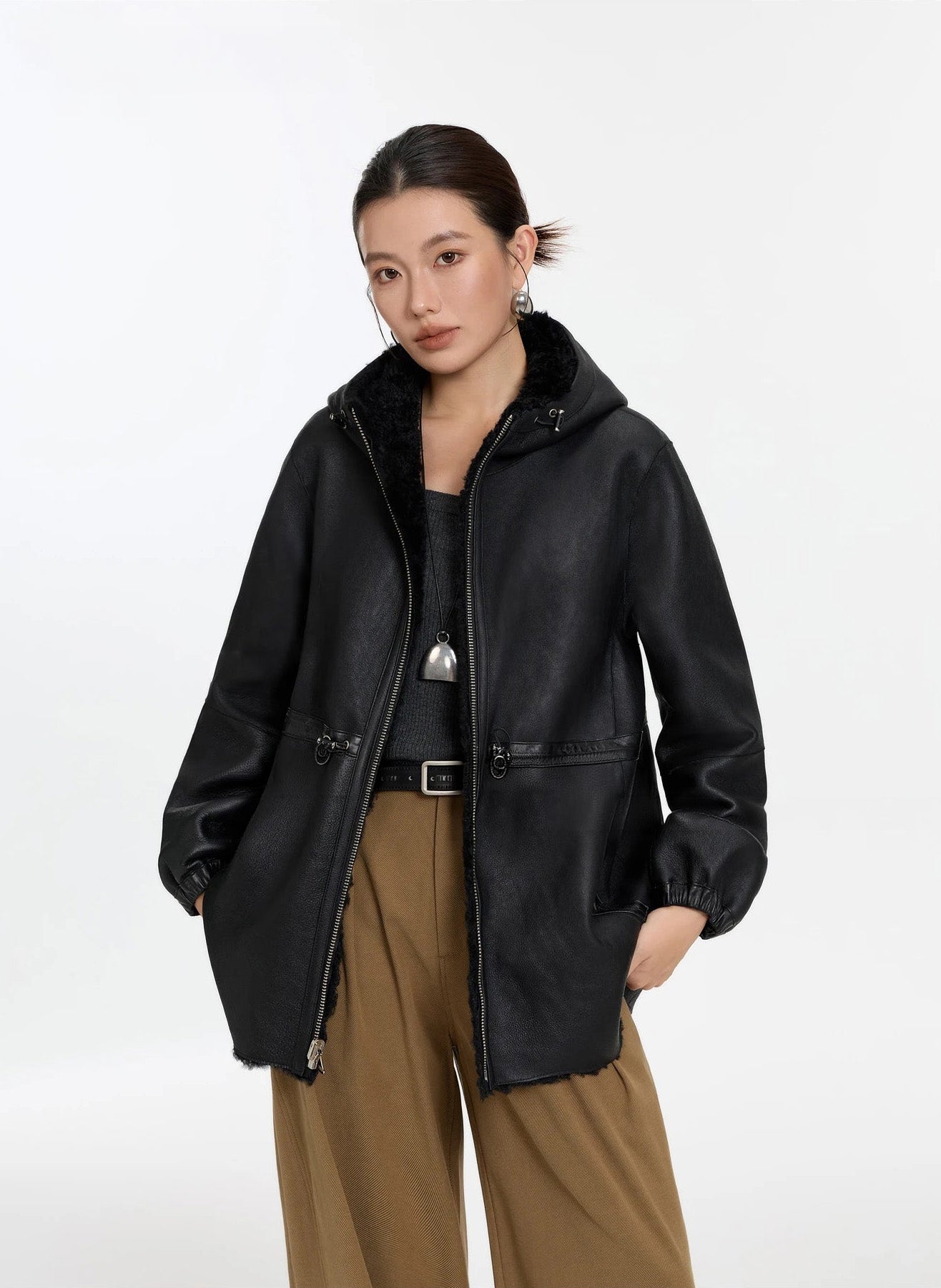 Model wearing the unzipped Night Swirling coat, lifting the hem with both hands, leather side — From Borcelleclothes.