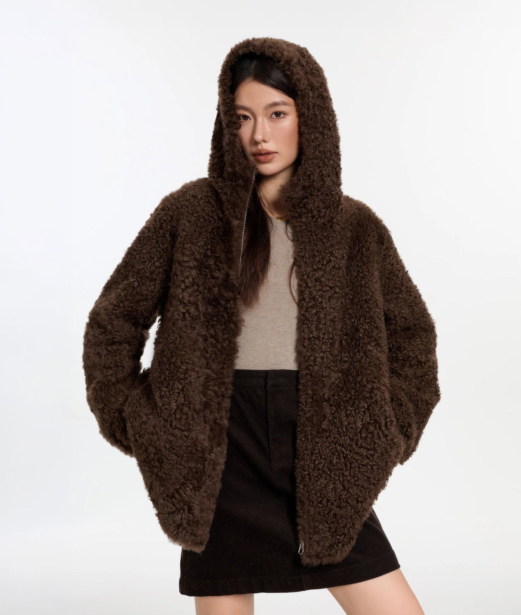 Model lifting the hem with both hands and hood up, Toffee Bloom coat, fur side — From Borcelleclothes