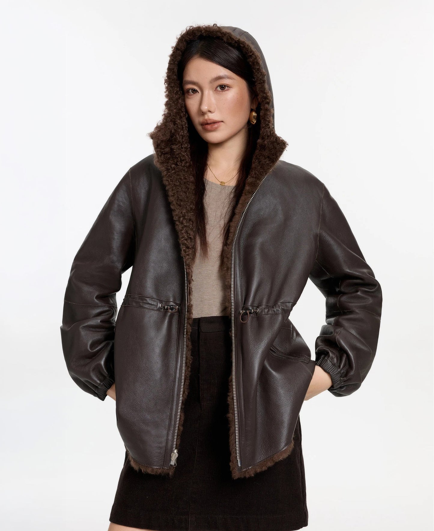 Model lifting the hem slightly with hood up, Toffee Bloom coat, leather side — From Borcelleclothes.