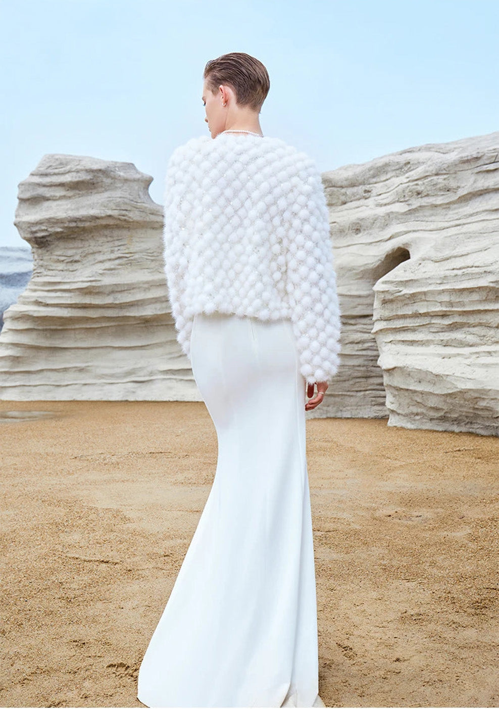 Model shown from the back, looking to the side while wearing the White Whimsy mink mosaic coat, highlighting the sleeve and neckline — From Borcelleclothes.