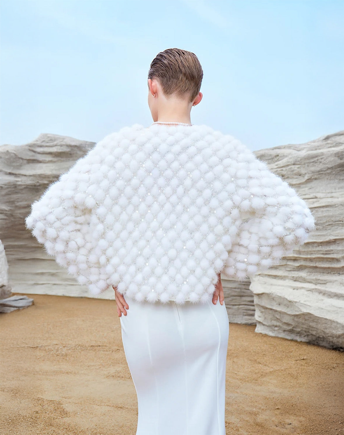 Model resting hands on hips while facing away in the White Whimsy mink mosaic coat, showcasing back construction and texture — From Borcelleclothes.