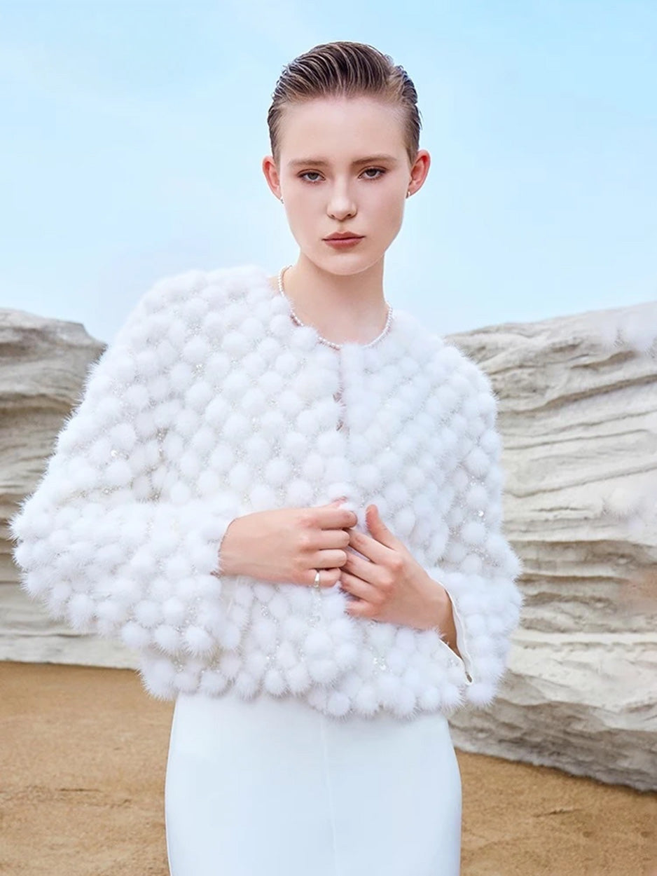 Model holding the front edges of the unfastened Women’s Inlaid Mink Mosaic Coat in White Whimsy — From Borcelleclothes.