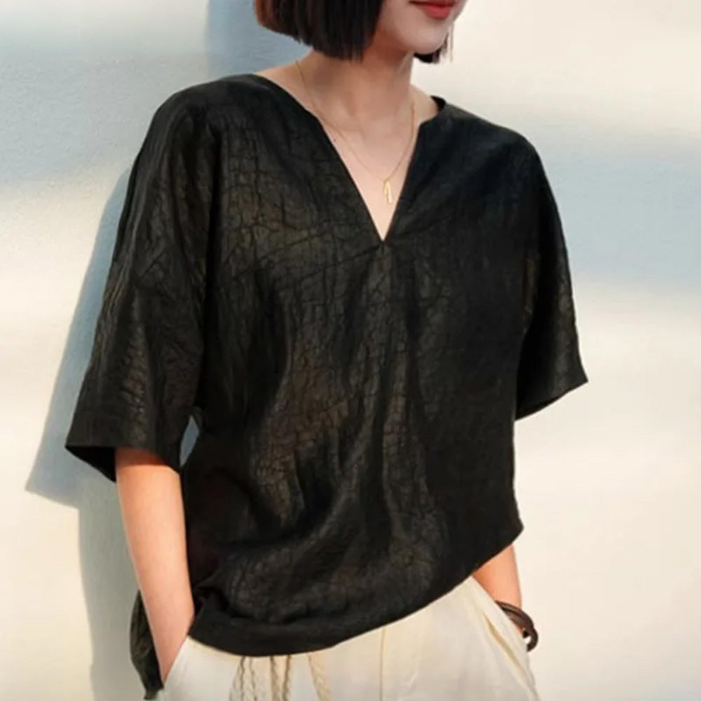 Three-quarter angle of the matte graphite Beyond Control silk top paired with white linen trousers, looking to the side — From Borcelleclothes.