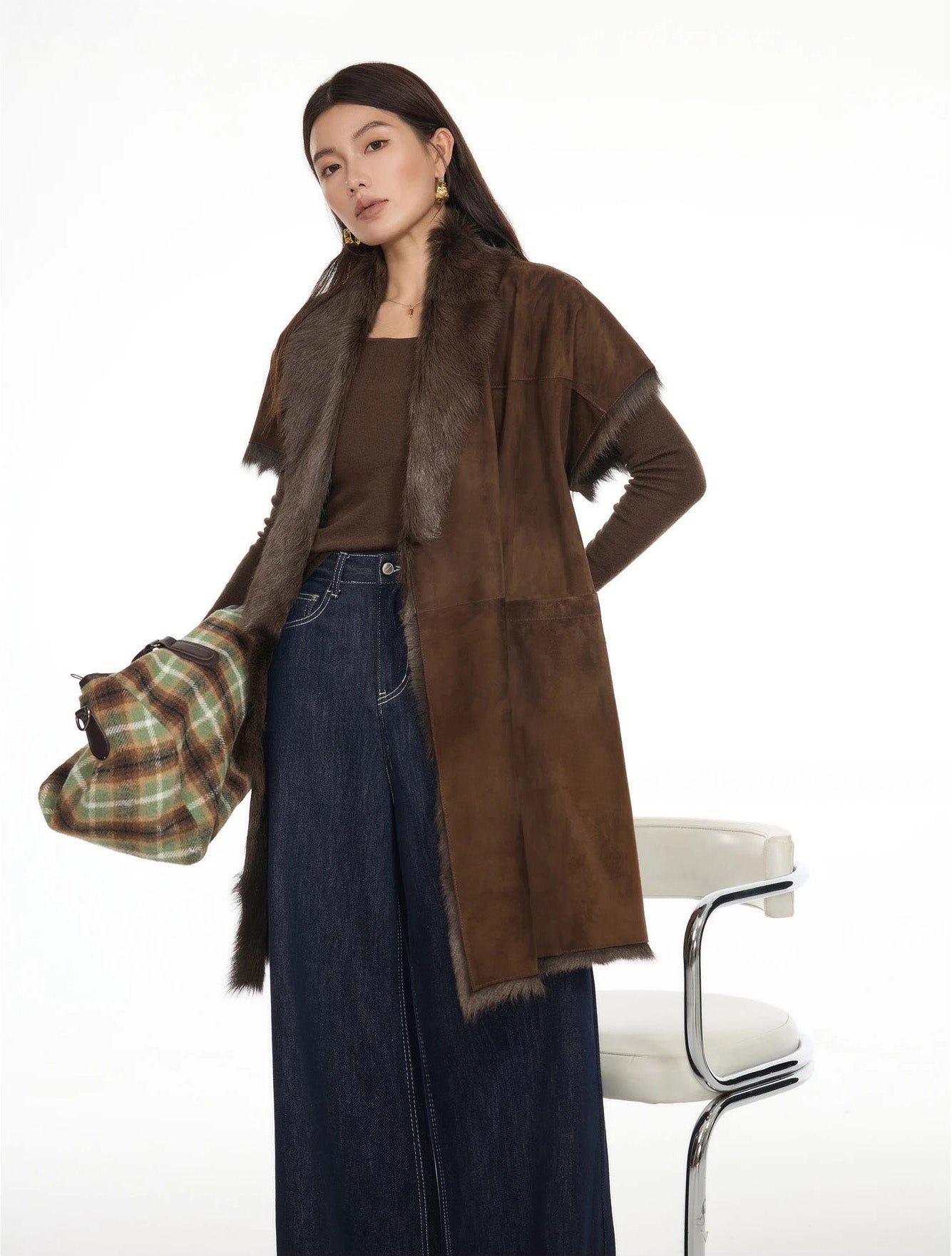 Model with one hand behind back, holding bag in other hand, wearing goatskin wrap jacket — From Borcelleclothes.