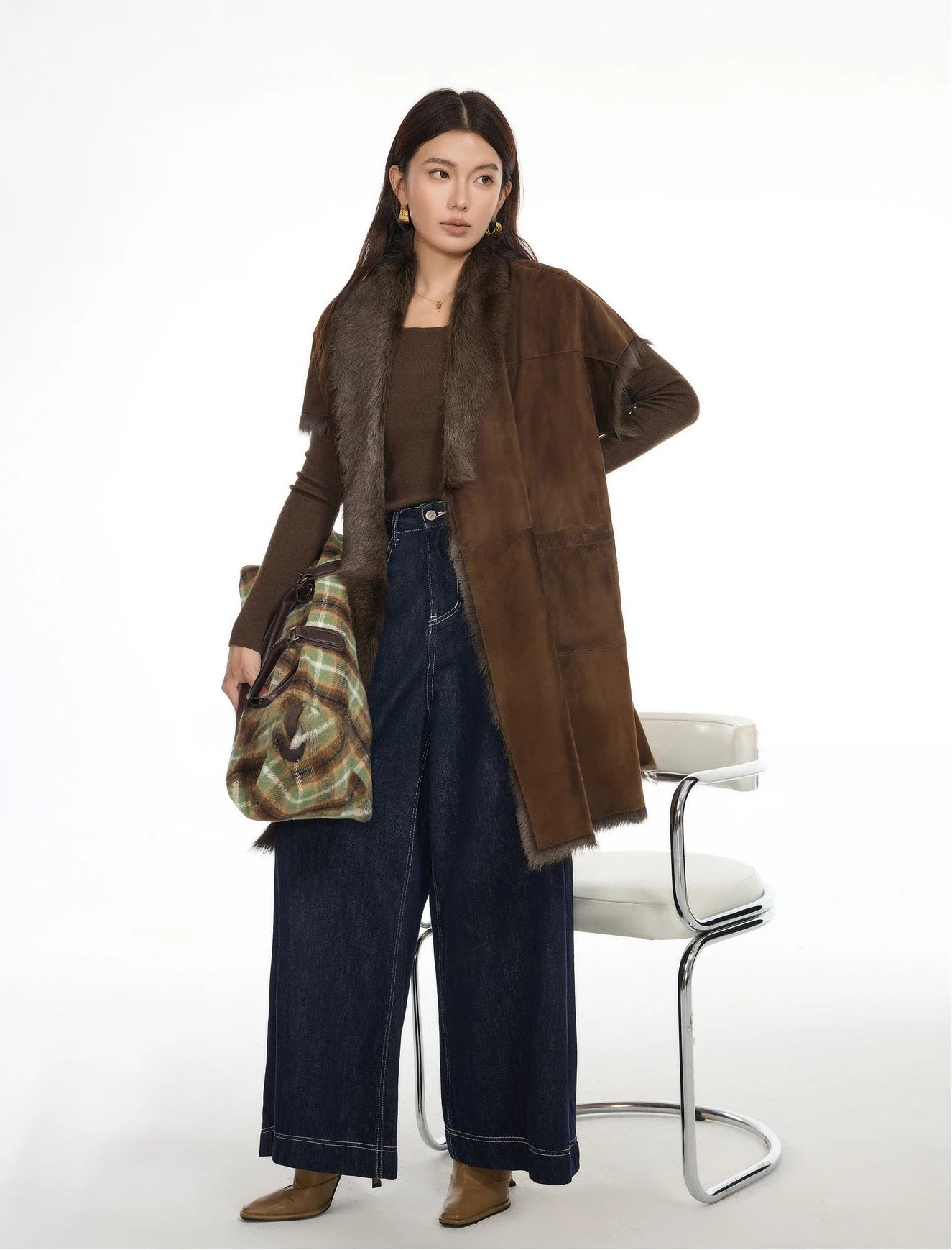 Model looking sideways while holding bag, jacket unfastened to reveal inner fur — From Borcelleclothes.