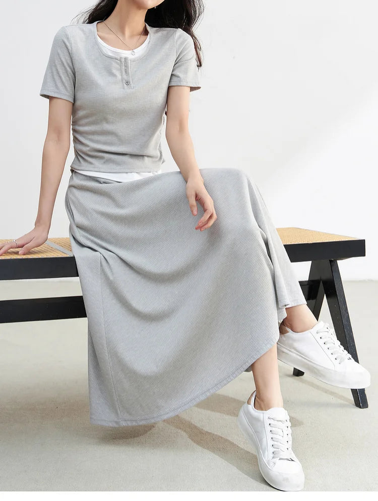Woman sitting on a bench with crossed legs, wearing the Incognito light grey knit set — From Borcelleclothes.