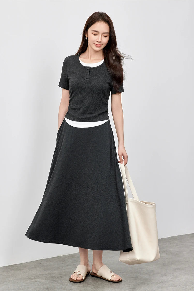 Stylish woman in a Mojo knit set, leaning slightly while holding a white handbag — From Borcelleclothes.