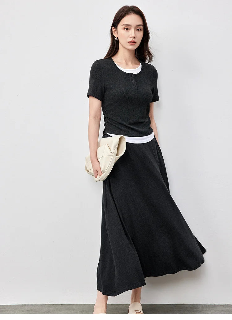 Woman moving gracefully in a Mojo dark grey flared knit set, showing the skirt's fluidity — From Borcelleclothes.