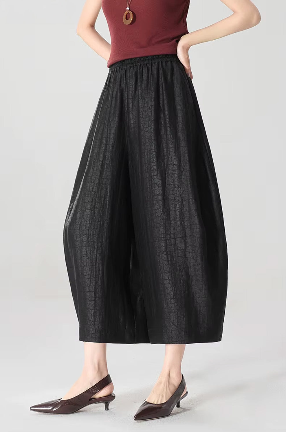 A woman with hands on her waist wearing black Xiangyunsha Mulberry silk lantern pants in Tortoise Ticket — From Borcelleclothes.