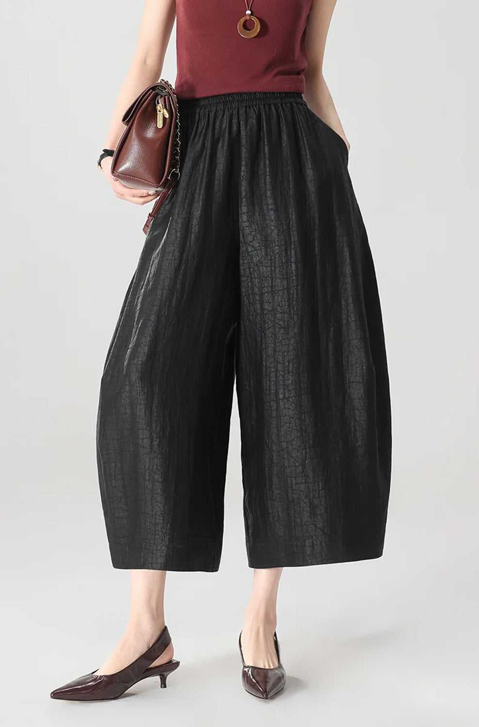 A woman holding a handbag while wearing black Xiangyunsha Mulberry silk lantern pants in Tortoise Ticket — From Borcelleclothes.